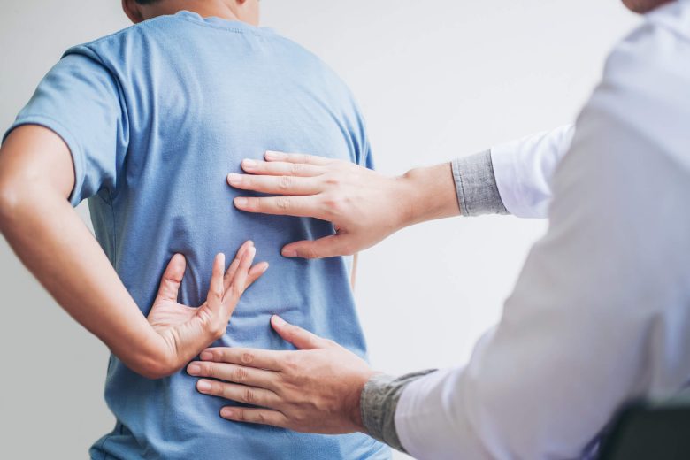 A physical therapist helps with a man's lower back pain.